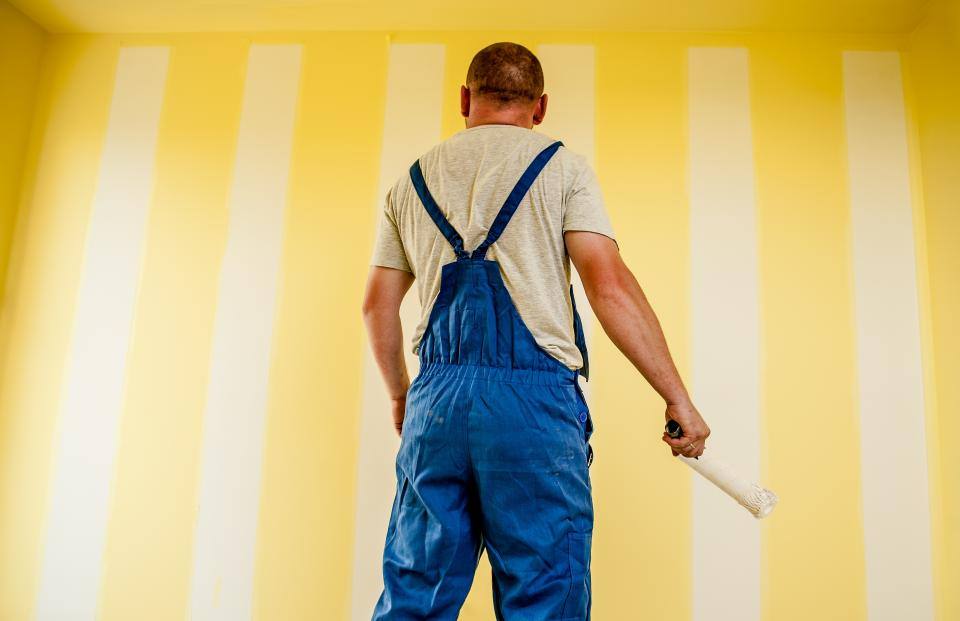 Painter rolling yellow paint on a wall